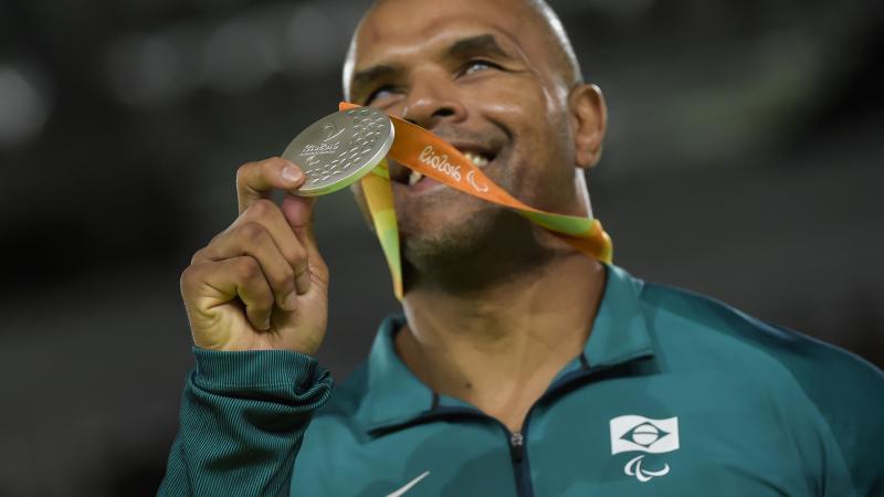 a male judoka holds up a silver medal