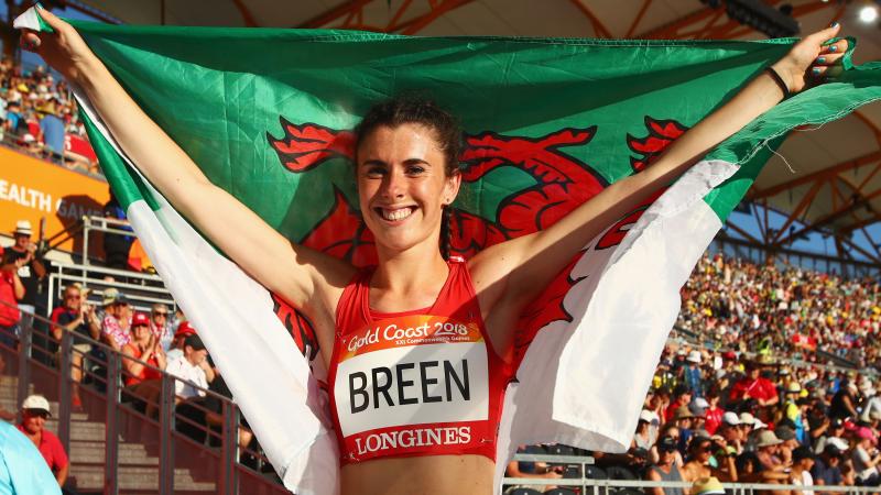 a female Para athlete holding up the Welsh flag