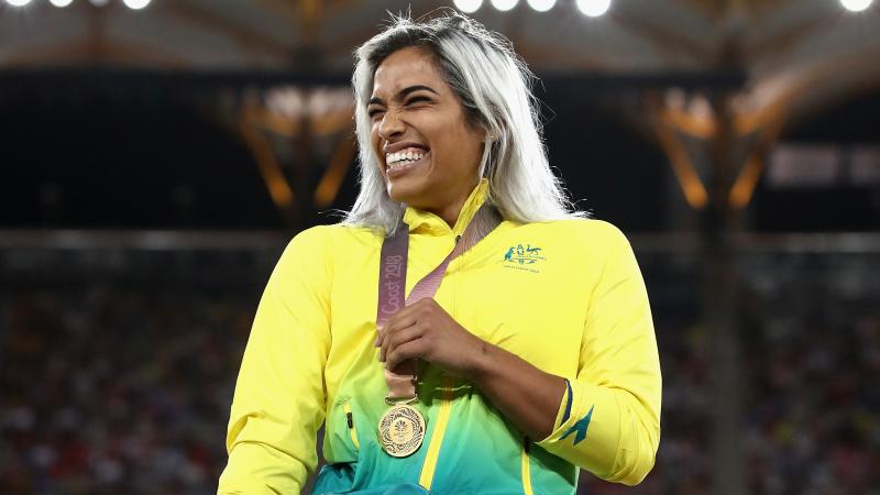 a female wheelchair racer laughs with her gold medal