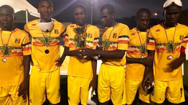 a group of blind footballers hold up a trophy