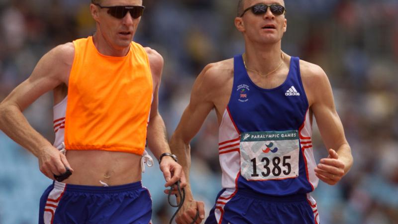 a male vision impaired runner and his guide during a race