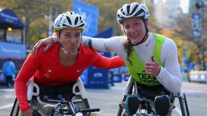 two female wheelchair racers arm in arm at the finish line