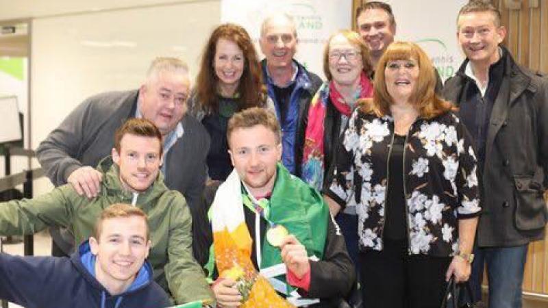Man in wheelchair with Irish flag around him and his family