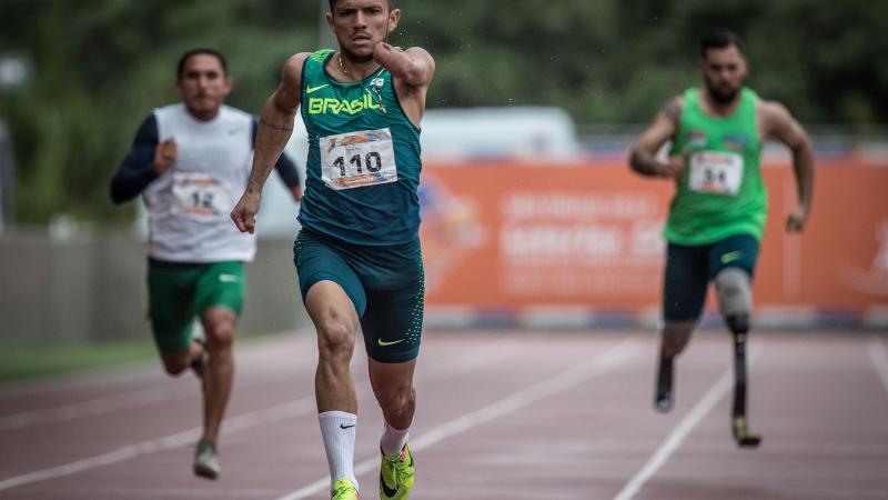 Three athletes running on an athletics track