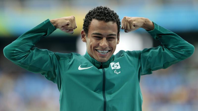 a male athlete raises his fists on the podium