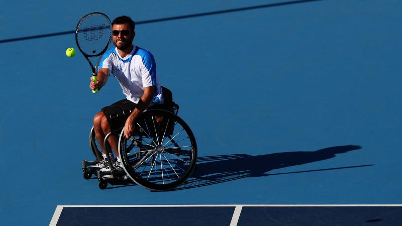 A male wheelchair tennis player takes a shot