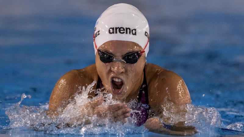 a female Para swimmer comes out of the water to take a breath