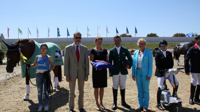 a group of people awarding a Para equestrian rider his medal