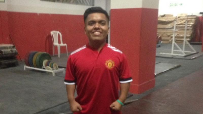 a male powerlifter standing in a Manchester United shirt
