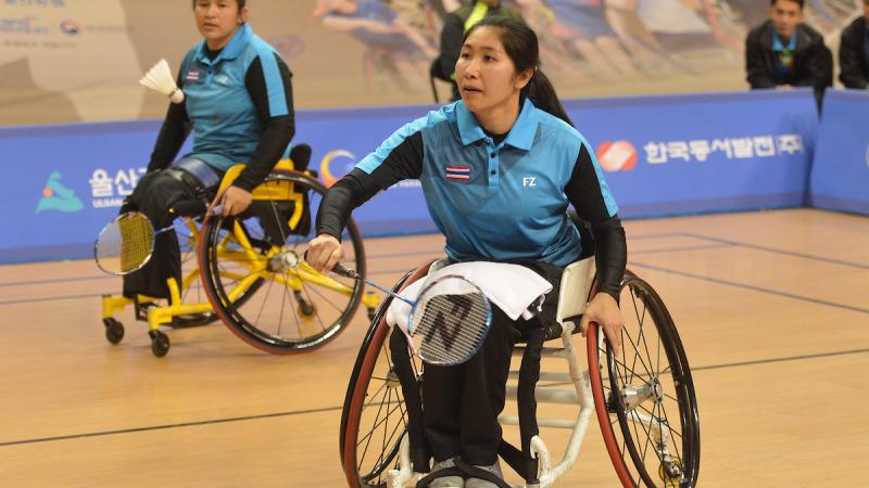 Woman badminton player in wheelchair hits a birdie