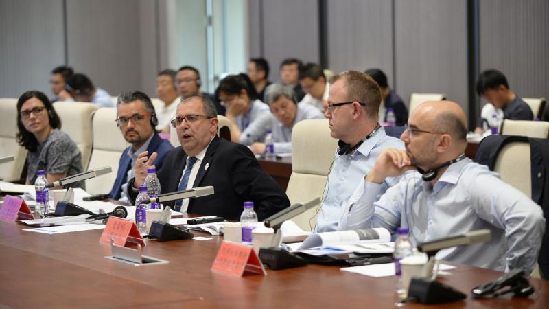 a group of men speaking at a table