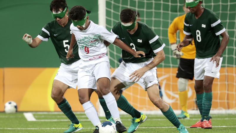 a group of blind football players in action on the pitch