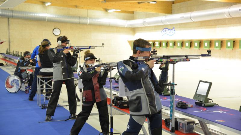 Five shooters practicing, one of them in a wheelchair