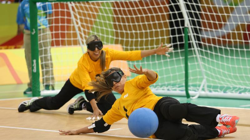 two female goalball players trying to stop a shot