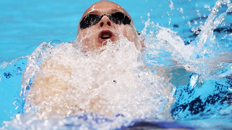 a male Para swimmer mid-backstroke