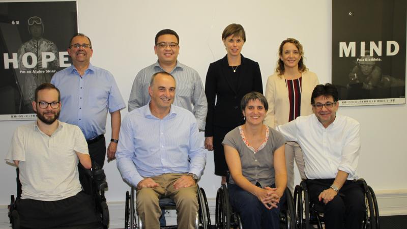 A group of eight people both standing and sitting smile for the camera