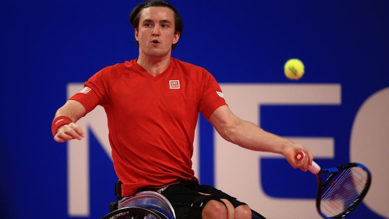 a male wheelchair tennis player takes a shot