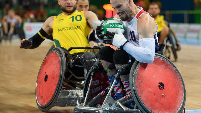 two male wheelchair rugby players fight for the ball