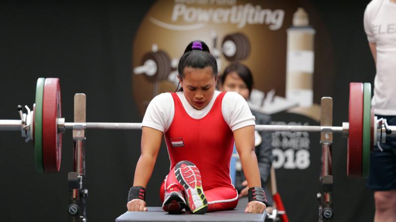 a female powerlifter prepares to lift by sitting on the bench