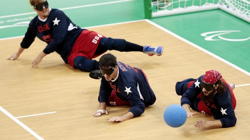a male and female goalball player dive to save a shot