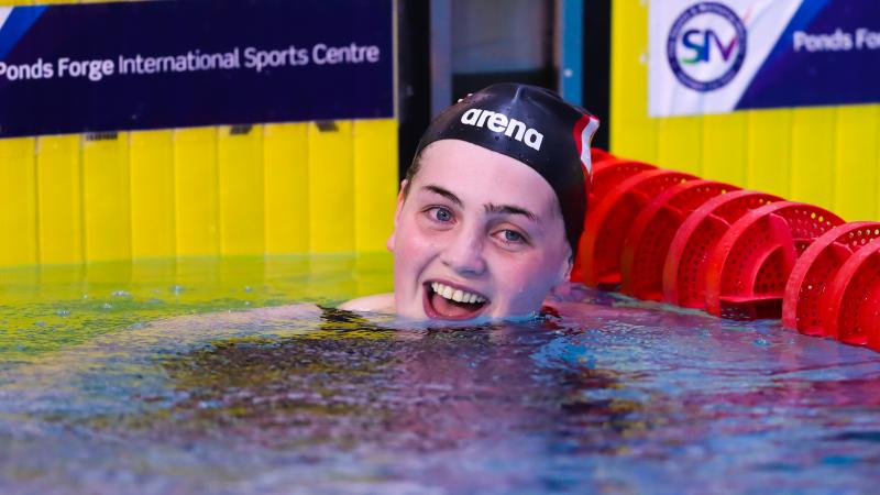 a female swimmer smiles in the pool after winning her race