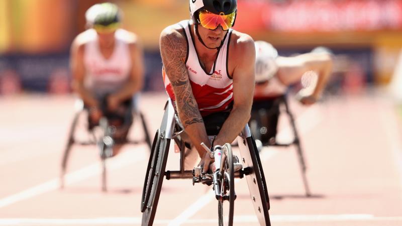 a male wheelchair racer crosses the finish line