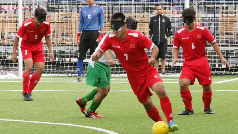 A male blind footballer dribbles past another player