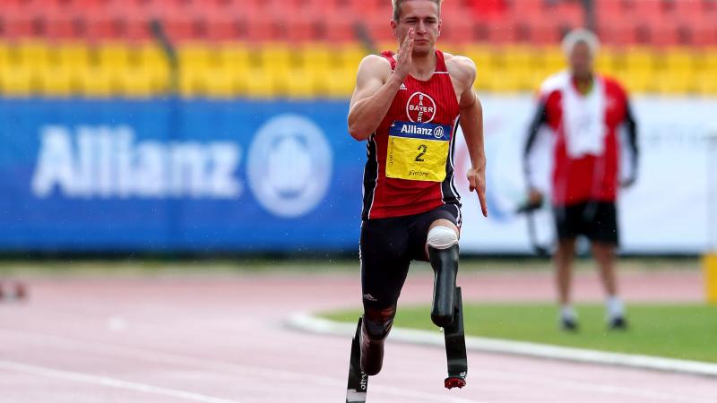 a male double amputee sprinter runs towards the finish line