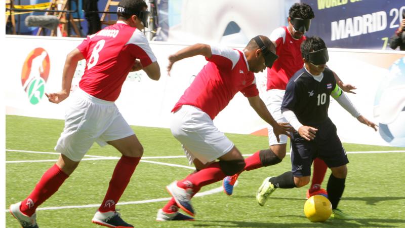 a group of blind footballers contesting a ball