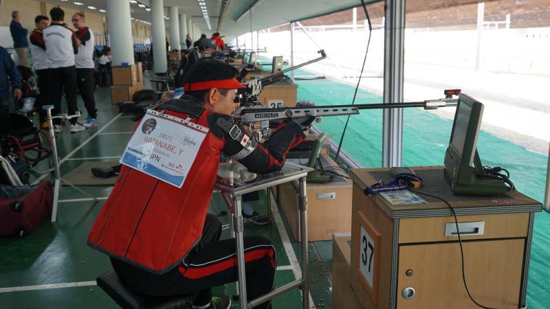 a male Para shooter takes a shot with a rifle