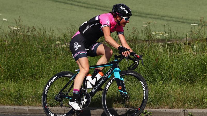 a female Para cyclist rides down a road