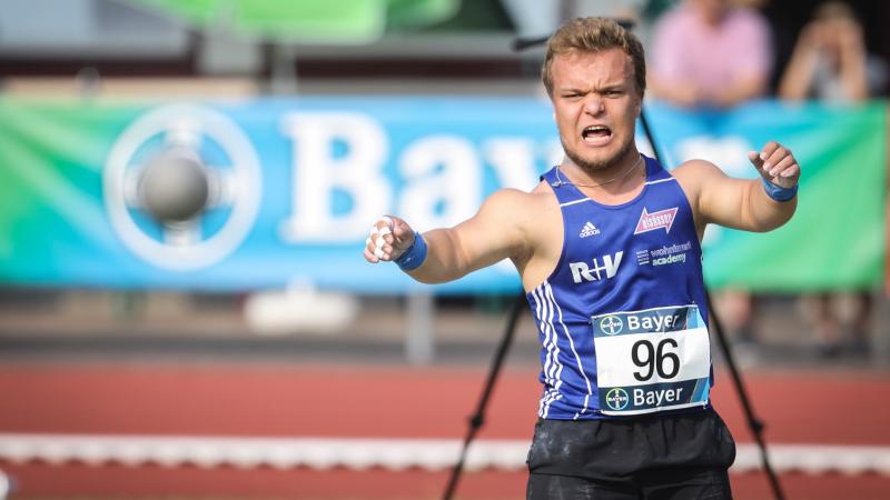 a male thrower of short stature launches a shot put