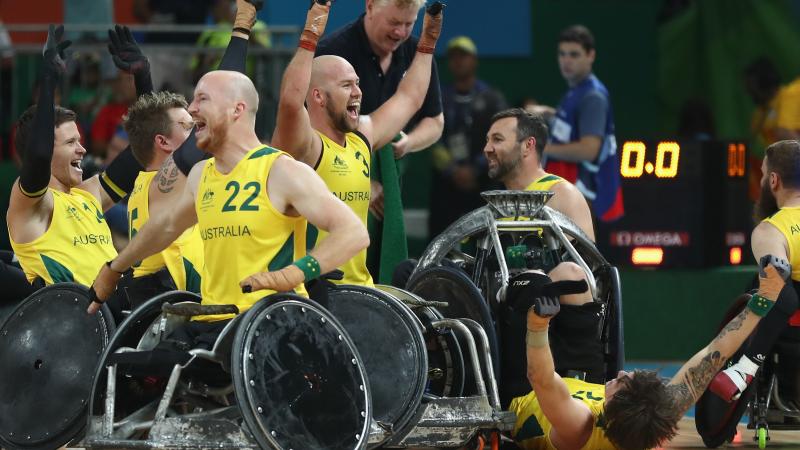 a group of male wheelchair rugby players celebrating on the court