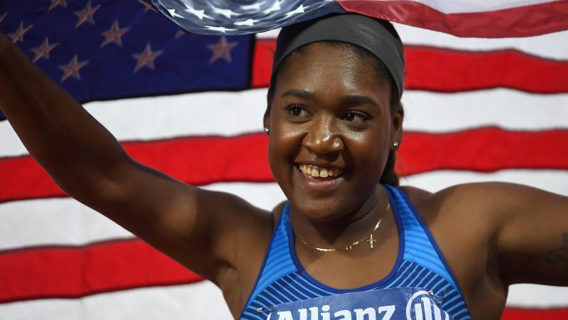 a female Para athlete smiling and holding an American flag