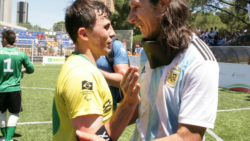 two blind footballers hugging on the pitch