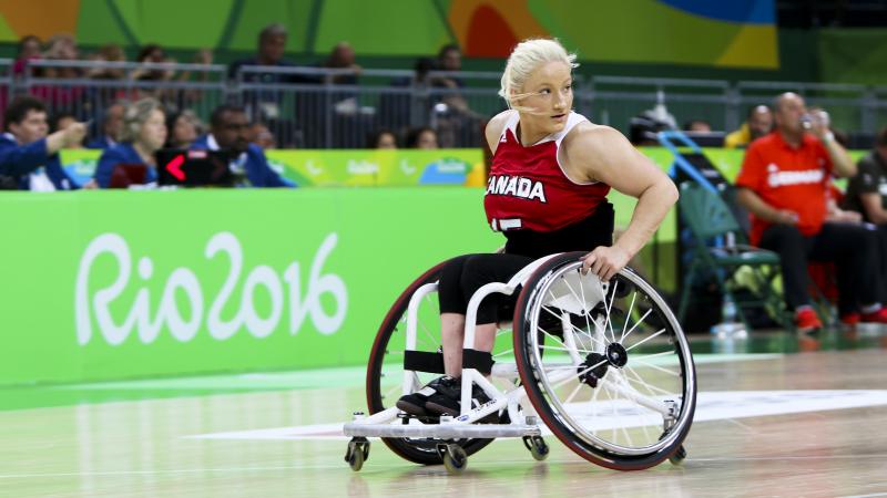 Women in wheelchair dribbles basketball
