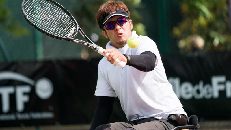 a male wheelchair tennis player goes for a backhand shot
