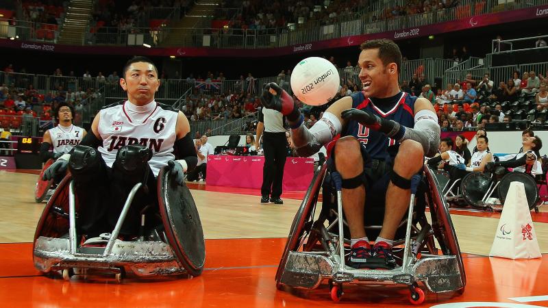 two male wheelchair rugby players with one holding a ball 