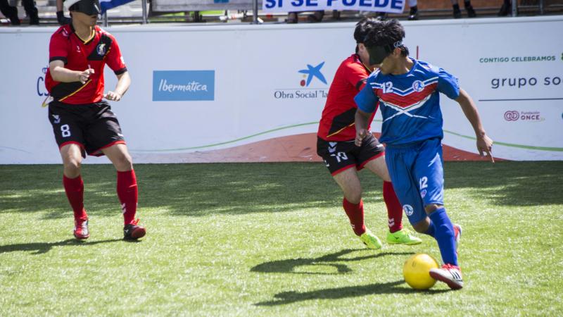 a male blind footballer runs with the ball