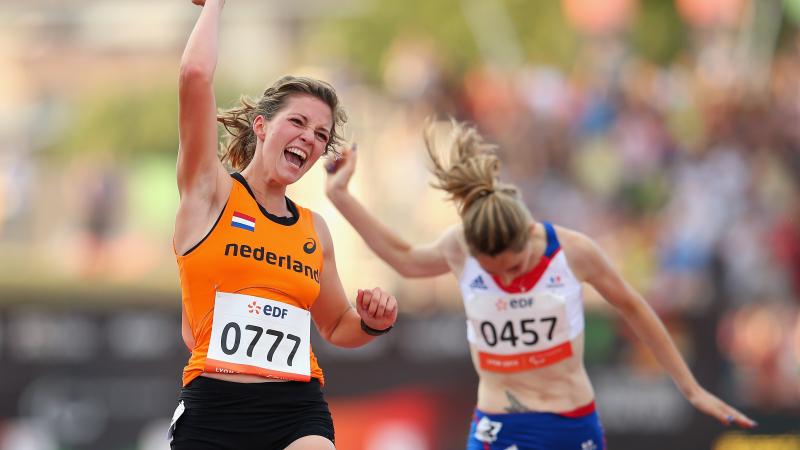a female amputee sprinter punches the air as she crosses the finish line