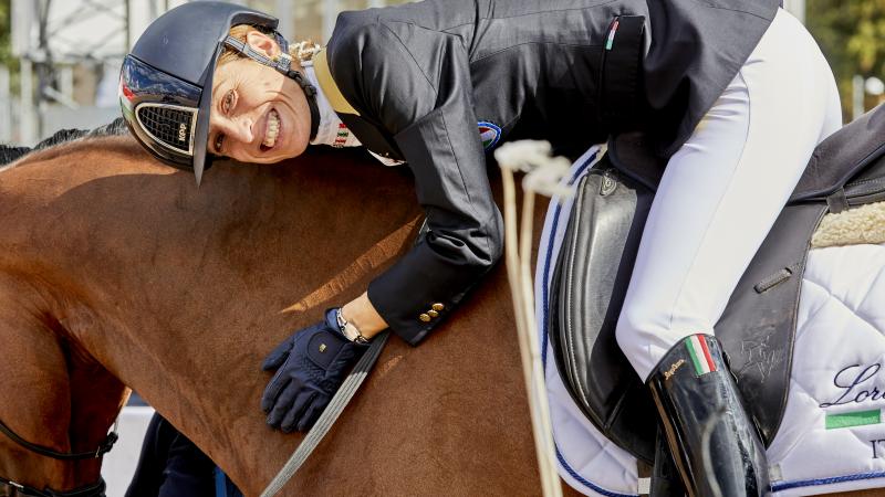 a female Para equestrian rider hugging her horse