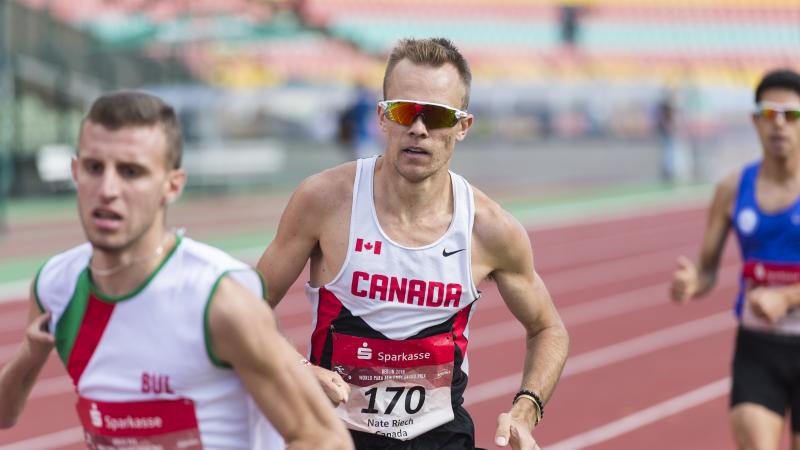 a male Para athlete overtakes another runner on the track