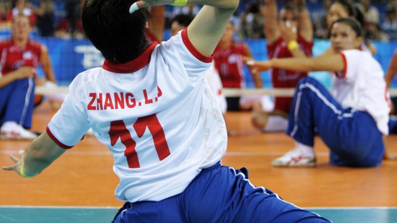 a female sitting volleyball player prepares to serve