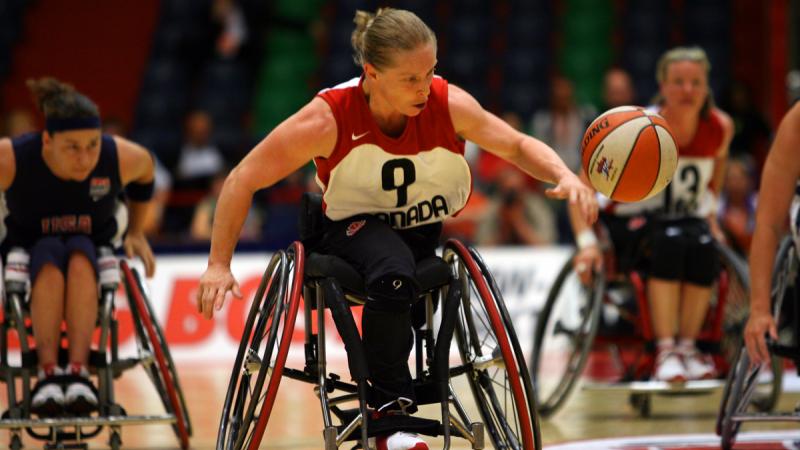 a female wheelchair basketballer dribbles the ball