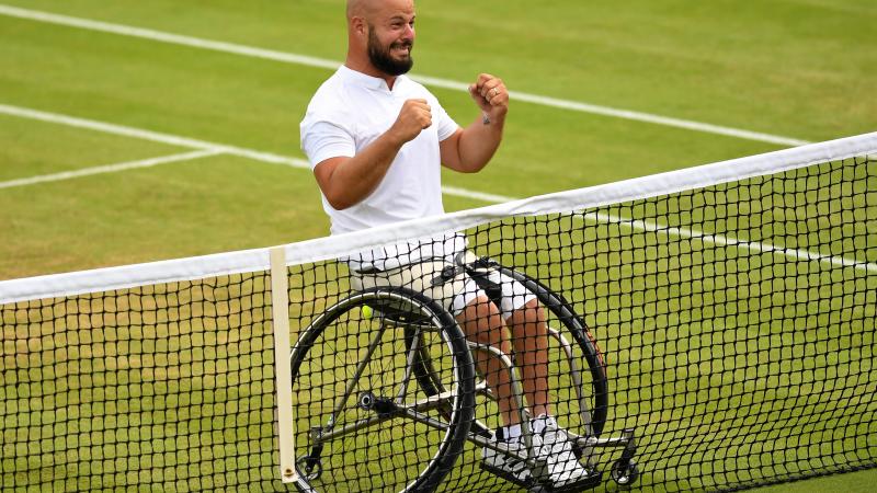 male wheelchair tennis player Stefan Olsson raises his fists in celebration at the net