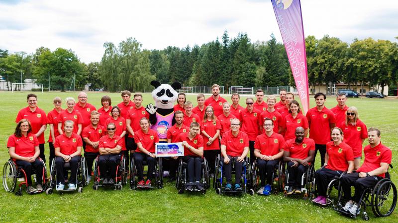 Group athletes standing and in wheelchairs meet Max the Para panda mascot