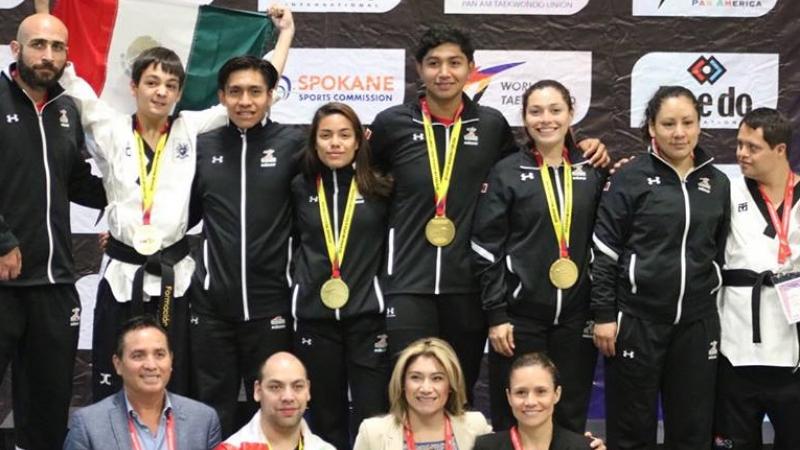 a group of male and female Para taekwondo fighters standing together with gold medals round their necks