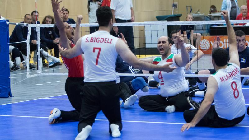 The Iranian men's sitting volleyball team throw their arms up in celebration on the court