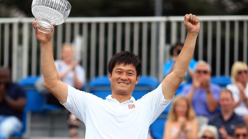 Male wheelchair tennis player Shingo Kunieda holds up a glass trophy