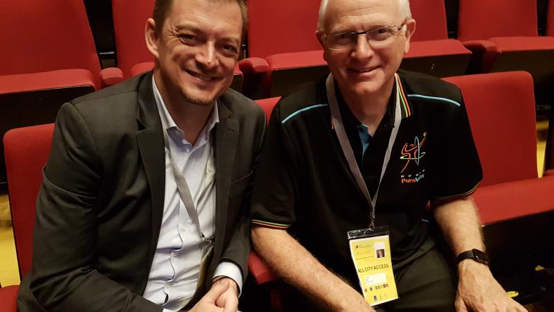 two men, Andrew Parsons and Barry Couzner, smiling and shaking hands